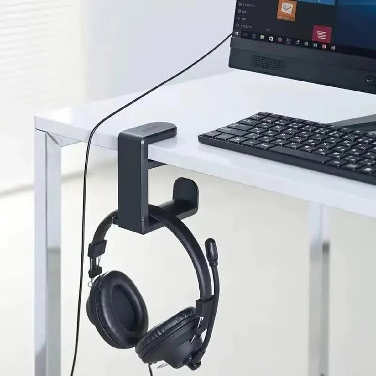 HANG clamped to a white desk holding headphones